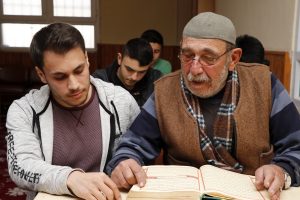 Kur'an-ı Kerim öğrenmek için kursa giden ressam, kursiyerlere hat öğretiyor